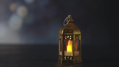 Üzerinde LED mum bulunan küçük yaldızlı bir Fas kule feneri bulanık bir bokeh ile karanlık bir taş zemin üzerinde duruyor. Yan taraftan, yavaş çekimde yakın çekimle ve yakınlaştırmayla çekilmiş. Şenlikli dekor konsepti, Ramazan Kareem.