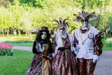 Grand-Bigard Şatosu, Belçika - 27 Nisan 2025. Maya çiçek festivali için düzenlenen çiçek sergisi sırasında Venedik 'in parlak kostümlü üç kişinin portresi, yakın çekim..