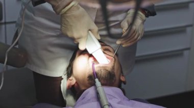 Tanınmayan bir dişçi, damar içi tarayıcı kullanarak güzel bir erkek hastanın sol dişlerinin dijital üç boyutlu modelini oluşturur. Yan görüntüyü yavaş çekimde çek. Konsept: diş sağlığı, teknoloji kullanımı, dişçiler iş günü.