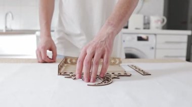 Genç, tanınmayan beyaz bir adam bir masada duruyor, oyulmuş bir yarım ay, bir yıldız ve bir kitap ile yan parçalarını topluyor ve onları oyulmuş ahşap bir tepsi oluşturarak deliklere sokuyor. Yakın çekim, yavaş çekimde yan görünüm