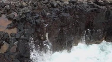Atlas Okyanusu 'nun kuzey kıyısındaki volkanik bir uçuruma çarpan dalgaların atmosferik görüntüsü, yukarıdan yakından ve yavaş çekimde izleniyor. Güzel deniz manzarası konsepti.