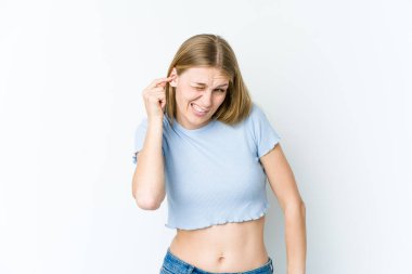 Beyaz arka planda izole edilmiş genç sarışın kadın kulaklarını elleriyle kapatıyor..