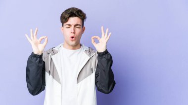 Mor arka planda izole edilmiş genç beyaz adam sıkı çalışma gününden sonra rahatlıyor. Yoga yapıyor..