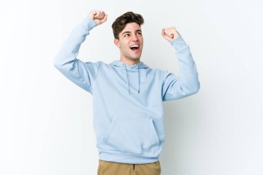 Beyaz arka planda izole edilmiş genç beyaz bir adam zaferden sonra yumruğunu kaldırıyor, kazanan konsept.