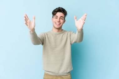 Mavi arka planda izole edilmiş genç beyaz adam kameraya sarıldığı için kendinden emin hissediyor..