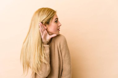 Genç, sarışın, beyaz bir kadın bir dedikoduyu dinlemeye çalışıyor..