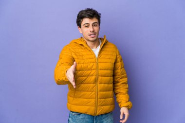 Genç havalı adam kameraya elini uzatıp selam veriyor..