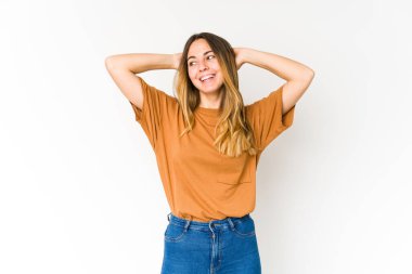 Beyaz arka planda soyutlanmış beyaz tenli genç bir kadın kendini güvende hissediyor, elleri başının arkasında..