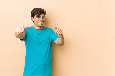 Havalı genç adam iki parmağını da kaldırıyor, gülümsüyor ve kendinden emin..