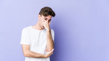 Mor arka planda izole olmuş genç beyaz adam güler, kaygısız, doğal duygular.