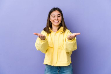 Beyaz bir kadın elinde avuç içi bir şeyle kameraya sunuyor..