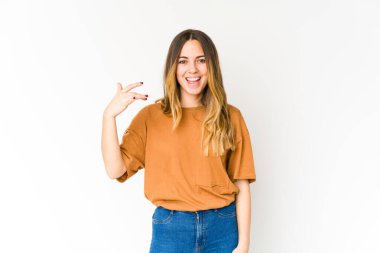 Beyaz arka planda izole edilmiş genç beyaz bir kadın bir şeye gülüyor, elleriyle ağzını kapatıyor..