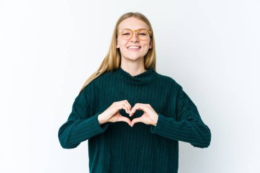 Beyaz arka planda izole edilmiş genç sarışın kadın gülümsüyor ve elleriyle kalp şeklini gösteriyor..