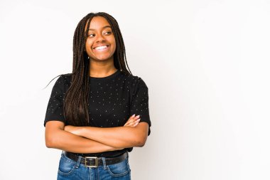 Beyaz arka planda izole edilmiş genç Afrikalı Amerikalı kadın kollarını kavuşturarak gülümsüyor..