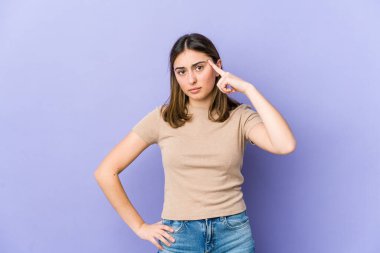 Kafkasyalı genç bir kadın şakağı parmağıyla işaret ediyor, düşünüyor, bir göreve odaklanıyor..