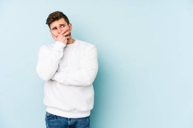 Kafkasyalı genç adam mavi arka planda izole edilmiş korkmuş ve korkmuş..