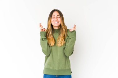 Beyaz arka planda izole genç beyaz kadın şans dilemek için parmaklarını çapraz