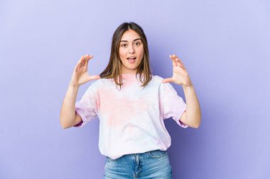 Beyaz bir kadın elinde avuç içi bir şeyle kameraya sunuyor..