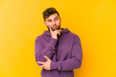 Kafkasyalı genç bir adam sarı arka planda izole edilmiş. Bir strateji planlıyor, bir iş yolu düşünüyor..