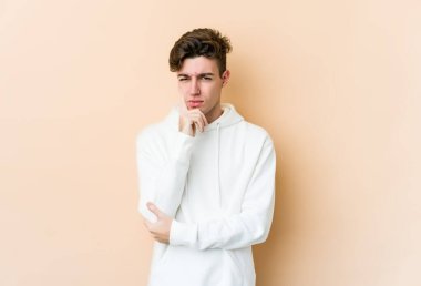 Beyazlı genç bir adam bej arka planda izole edilmiş. Bir strateji planlıyor, bir iş yolu düşünüyor..