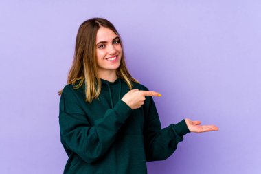 Mor arka planda izole edilmiş genç beyaz bir kadın, elinde bir fotokopi alanı tutarken heyecanlanıyor..