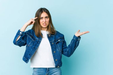 Genç beyaz kadın elinde bir ürünü tutuyor ve gösteriyor..