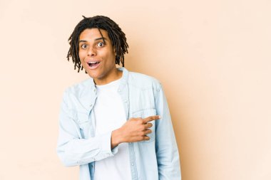 Genç Afrikalı Amerikalı Rasta adam gülümsüyor ve boş alanda bir şey gösteriyor..
