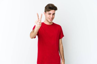 Beyaz arka planda izole edilmiş genç beyaz adam iki numarayı parmaklarıyla gösteriyor..