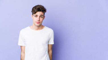 Mor arka planda izole edilmiş genç beyaz adam üzgün, ciddi yüz, sefil ve hoşnutsuz hissediyor.