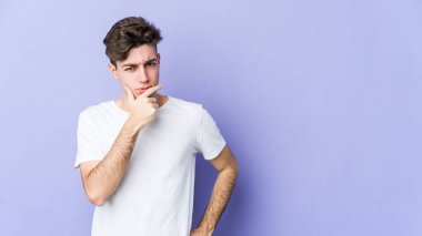 Mor arka planda izole edilmiş genç beyaz adam bir strateji planlıyor, bir işin nasıl olacağını düşünüyor..