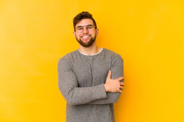 Sarı arka planda izole genç beyaz adam gülüyor ve eğleniyor..