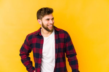 Sarı arka planda izole edilmiş genç beyaz adam gülüyor ve gözlerini kapıyor, rahatlamış ve mutlu hissediyor..