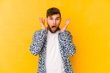 Sarı arka planda izole edilmiş genç beyaz adam şaşırdı ve şok oldu..