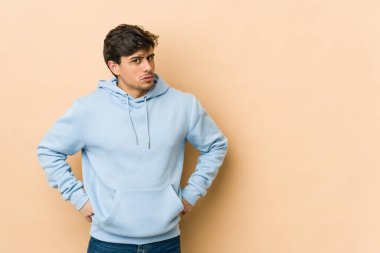 Hoşnutsuzca kaşlarını çatan, kollarını kavuşturan genç havalı bir adam..