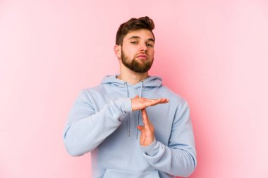 Pembe arka planda izole edilmiş genç beyaz adam bir mola hareketi gösteriyor..