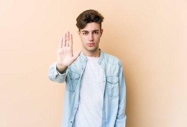Beyazlı genç bir adam bej arka planda izole edilmiş, elini uzatmış, dur işareti göstererek seni engelliyor..