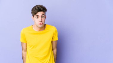 Mor arka planda izole genç beyaz adam omuzlarını silker ve gözleri açık kalır..