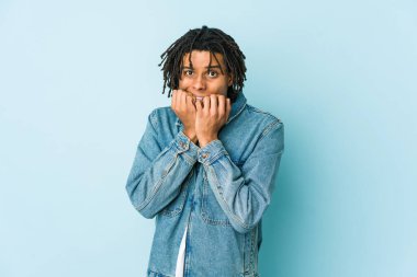 Genç siyah adam kot ceket giyiyor tırnaklarını yiyor, gergin ve çok endişeli..