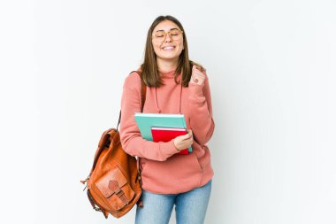 Beyaz fırında izole edilmiş genç bir kadın yumruğunu kaldırıyor, mutlu ve başarılı hissediyor. Zafer konsepti.