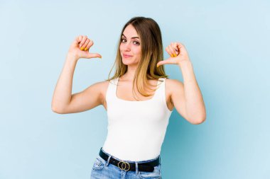 Mavi arka planda izole genç beyaz kadın gururlu ve kendinden emin hissediyor, örnek olarak..