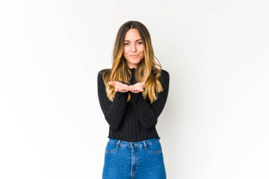 Beyaz arka planda izole edilmiş genç beyaz bir kadın dudaklarını katlıyor ve hava öpücüğü yollamak için avuç içleri tutuyor..