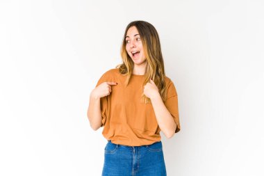 Beyaz arka planda izole edilmiş genç beyaz bir kadın parmağını göstererek şaşırdı, geniş bir gülümsemeyle..