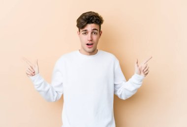 Beyazların arka planında izole edilmiş genç beyaz adam farklı kopya alanlarını gösteriyor, birini seçiyor, parmaklarıyla gösteriyor..