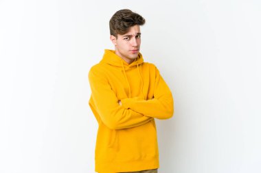 Beyaz arka planda izole edilmiş genç beyaz bir adam şüpheli, belirsiz, seni muayene ediyor..