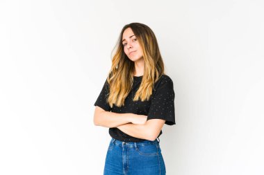 Beyaz arka planda izole edilmiş genç beyaz kadın şüpheli, belirsiz, seni muayene ediyor..