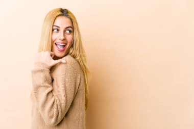 Genç sarışın beyaz kadın başparmağıyla işaret ediyor, gülüyor ve kaygısız..