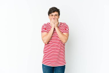 Genç, havalı bir adam bir şeye gülüyor, elleriyle ağzını kapatıyor..