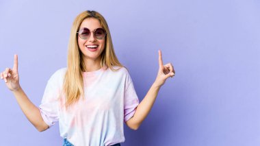 Sarışın, beyaz bir kadın iki elini de havaya kaldırarak boş bir alan gösterdiğini gösteriyor..