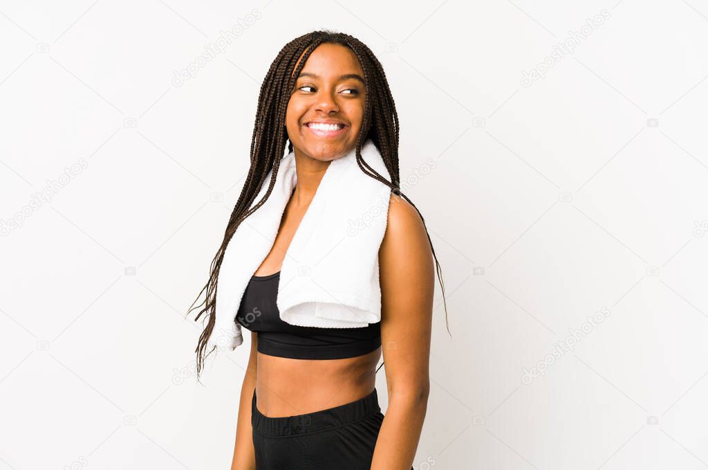 Young african american sport woman isolated looks aside smiling, cheerful and pleasant.