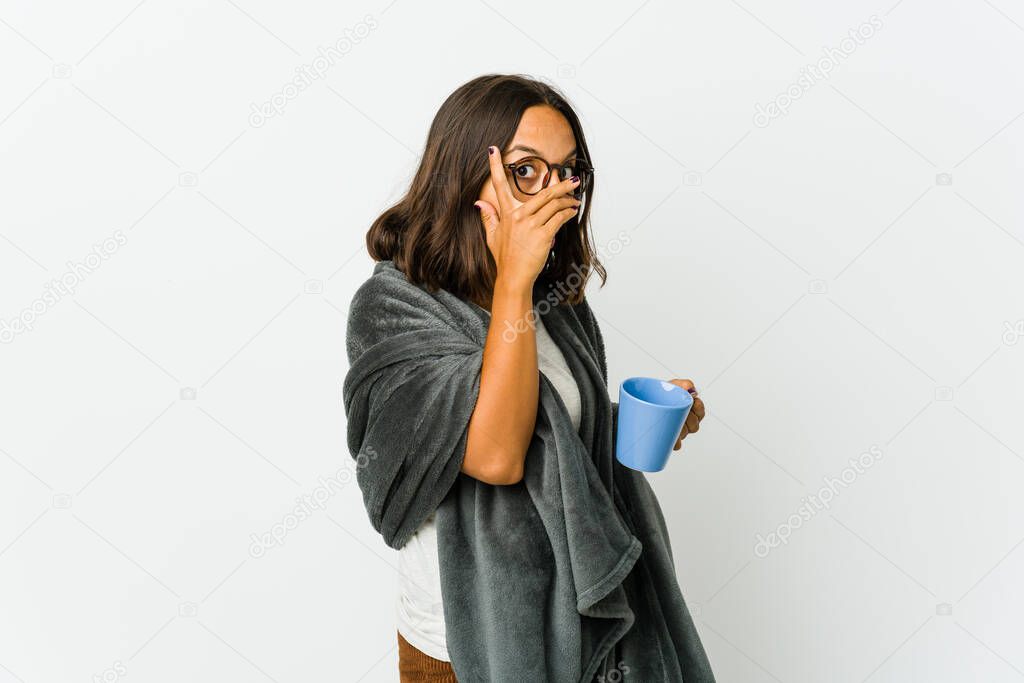 Young latin woman with blanket isolated on white background blink through fingers frightened and nervous.